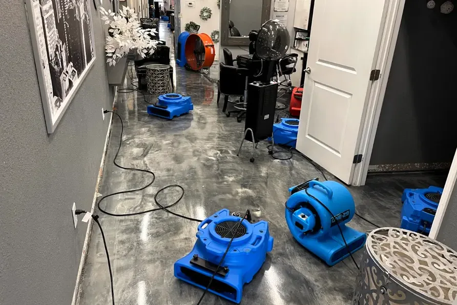 Blue air movers lined up to dry a hallway with a wet floor