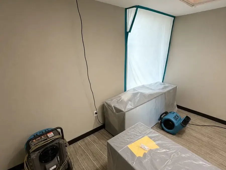 Plastic containment sheeting and air movers set up in an emptied room during structural drying